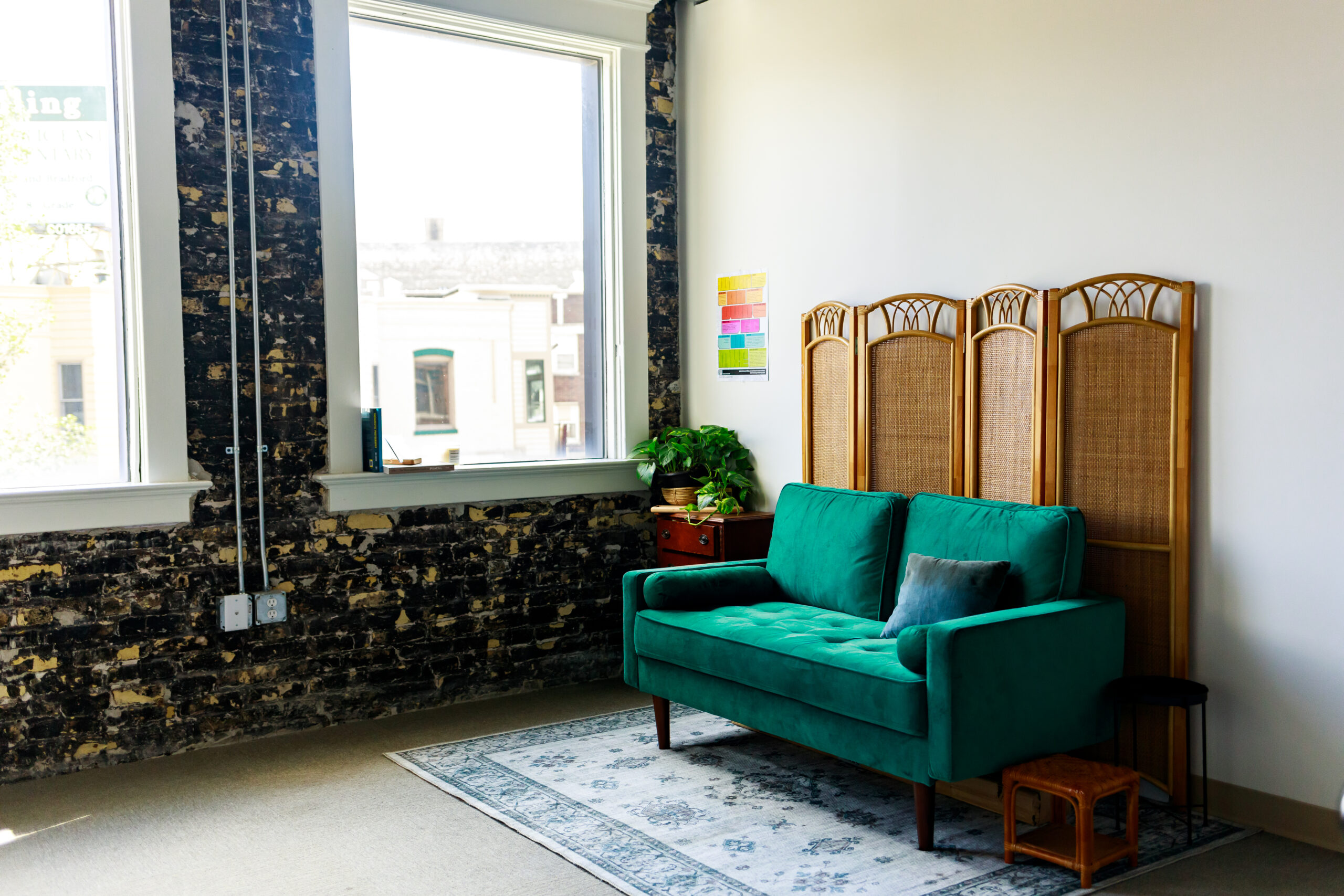 portrait photographer studio space with green couch, large windows and exposed cream city brick
