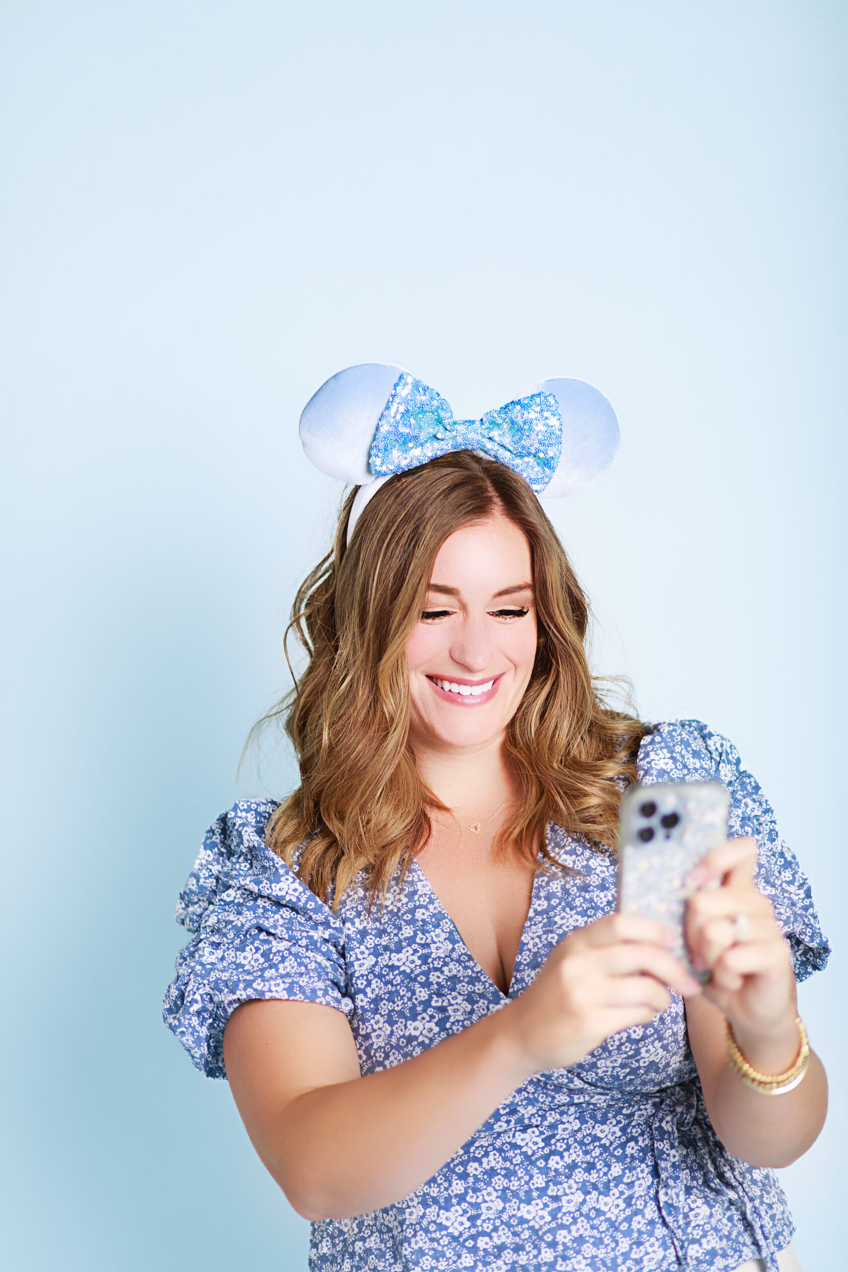 woman holding a phone with Disney scenes on the case