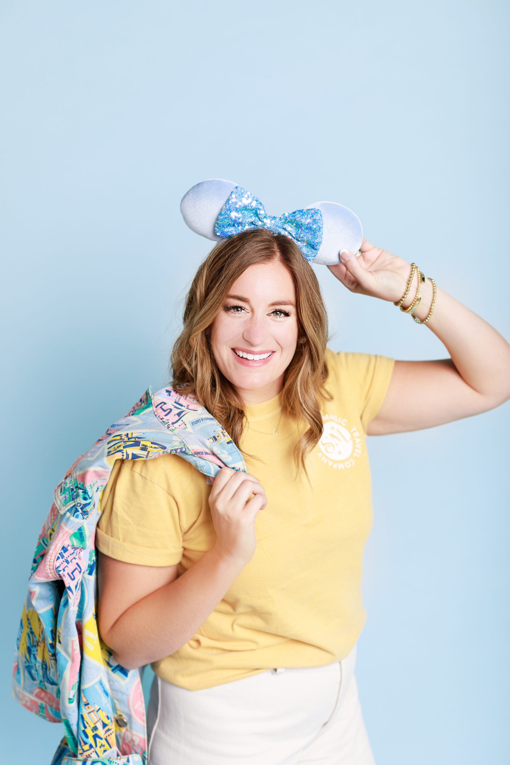disney travel planner holding Mickey Mouse ears and smiling 